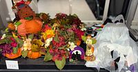 Photo showing assorted Halloween felt decorations including a scarecrow figure, ghost figure, colorful faux pumpkin flower arrangements, and other small Halloween decor.