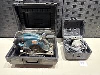 Black and Decker Wood Hawk electric saw and Porter Cable electric sander in their cases, viewed from front.