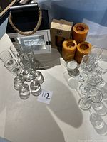 Overview of candle holders and candles including three brown candles, a boxed candle holder, a white decorative holder with rope handle, and multiple clear glass candle holders.
