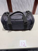 Grey camera carrying bag with handles and side zippers shown closed