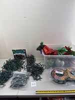 Overview of colored and white Christmas string lights, light clips, and two reels on a table.