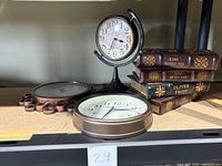 Photo of three battery operated clocks and four false books on a shelf.