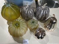 Seven glass pumpkins of various sizes and finishes arranged on table