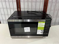 Front view of Hamilton Beach microwave oven, showing black stainless steel finish and closed door with control panel to the right side.