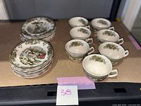 Full view showing 7 tea cups, 8 saucers, and 8 small bowls arranged on surface