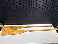 Full length view of two Navajo Brand wooden oars laid side by side, showing the general shape and length.