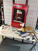 Photo showing assortment of metal and cardboard yard decorations and wooden snowman on table