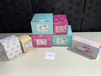 Seven boxed collectible figurines and one boxed votive box arranged on a table, showing all original product packaging.