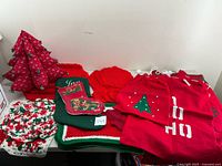 Four Santa’s toy sacks with holiday patterns and assorted crocheted placemats including a red-and-white circular placemat and green placemat with multicolor accents.