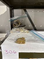 Jewelry items packed in plastic bags showing multiple gold tone chains and bracelets, some tangled or piled together.