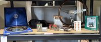 Multiple vintage car accessories including wooden steering wheel, radio, and tray arranged on shelf.