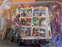 Large plastic tote filled with loose baseball cards in zipper bags and binder pages