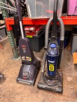 Both upright vacuums side by side showing full view of Bissell (left) and Eureka Power Plus (right) units