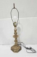 Full view of brass lamp with harp, finial, bulb and cord