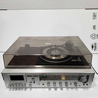 Front view of Sharp stereo music center showing tuner scale, control panel, tape slot and dust-covered turntable