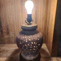 Lamp lit showing carved wood base with floral cutouts