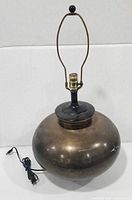 Front view showing round brass body, harp, finial, cord