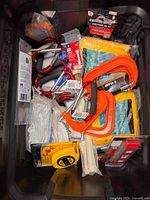 Overview of tote showing C-clamps, booster cables, rope, tape measure and several cable tie packs