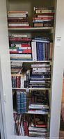 Photo of bookshelf filled with books stacked horizontally and vertically showing titles related to royal family, monarchy, and novels.