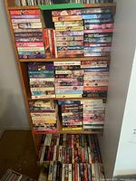 Full bookshelf filled with paperback romance novels spread across several shelves in good condition.