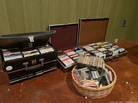 Photo showing four cases and one basket filled with cassette tapes arranged on a wooden floor against a wall