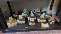 Full lot of ten Lilliput Lane miniature houses on original boxes, all approximately 2-3 inches tall, displayed on a fireplace hearth.
