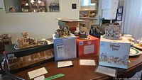 Four Lilliput Lane miniature building models displayed on table with original boxes and deeds visible