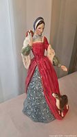 Front view of figurine showing red gown and dog at feet
