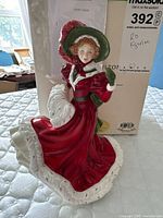 Front diagonal view of the Royal Doulton Christmas Day 2010 figurine with box behind it showing size and details.