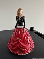Front view of the Royal Doulton Festive Stroll figurine showing the detailed black top and red skirt with bows.