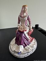 Front left three-quarter view of porcelain figurine seated on stone base