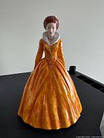 Front view of full figurine showing orange gown and white ruff collar