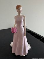 Front view of Royal Doulton figurine showing woman in pink dress holding rose bouquet