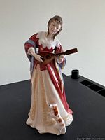 Front view of figurine showing full figure holding lute with dog at feet