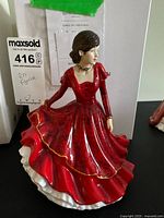 Front view of the Royal Doulton figurine showing full red dress with gold trim, head and arms.