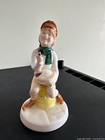 Front view of the Little Jack Horner figurine showing the character seated holding a pie and a plum, detailed clothing and facial features.