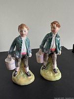 Front view of two vintage Royal Doulton Jack figurines showing detailed hand-painted features and the buckets they hold.