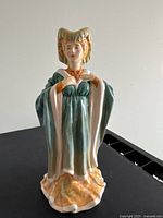 Front view showing green and white gown, orange headdress.