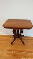 Full view of the antique Eastlake style wood parlour table on wheels showing the rectangular top and full base.
