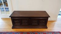Front view of vintage wooden blanket box showing carved front panels and overall condition.
