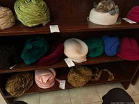 Full shelf display of various vintage ladies hats of multiple colors and textures, including floral and paisley patterns, wool, and smooth materials.