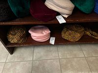 Shelf display of seven vintage ladies hats in various colors and styles including wool and polyester hats
