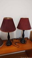 Two ceramic table lamps side by side on wooden surface showing full lamp and shade height and style.