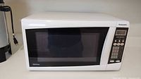 Front view showing the white Panasonic microwave with electronic control panel and black windowed door.