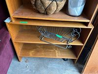 Laminate shelving unit showing three shelves with some contents on top shelf.