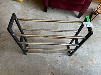 Top and side view of black metal shoe rack with horizontal rods in garage setting.