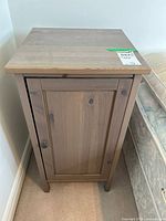 Front view of the wooden laminate side table showing paneled door with metal knob.