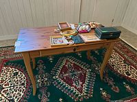 Full view of wooden table with items on top showing shape, size, and condition