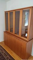 Full view of the teak veneer china cabinet showcasing the four glass doors on top and solid lower cabinet doors.