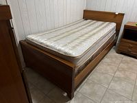 Full view of single-size bed frame showing wood veneer construction and mattress.